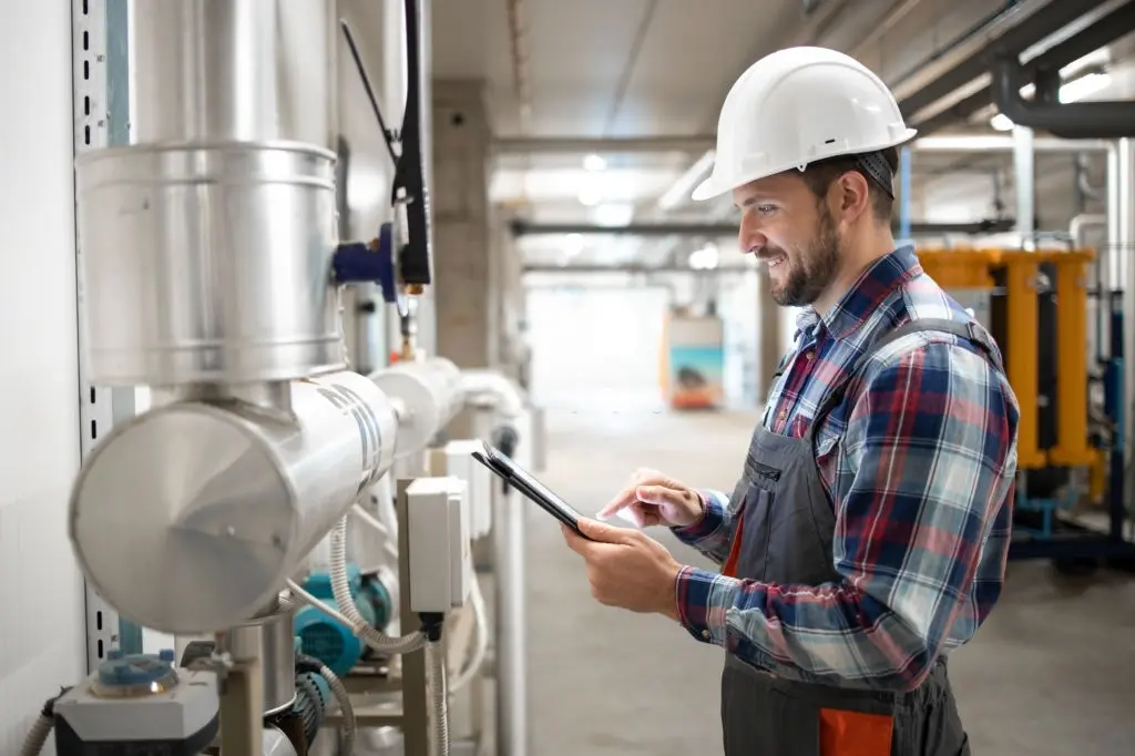 Technicien de service contrôlant les paramètres d’une installation de chauffage dans le local technique